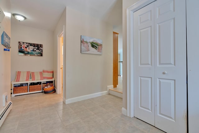 hallway featuring baseboard heating, baseboards, light tile patterned floors, and stairs