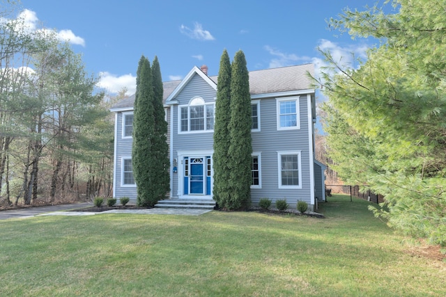 view of front of home featuring fence, a chimney, and a front yard