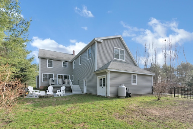 rear view of property with a deck, a patio area, a chimney, a lawn, and fence