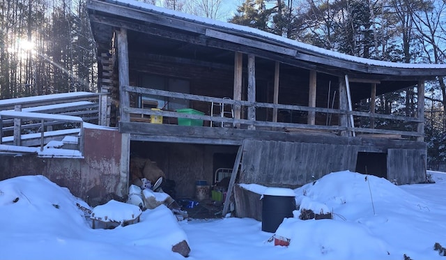 snow covered rear of property featuring a garage and metal roof