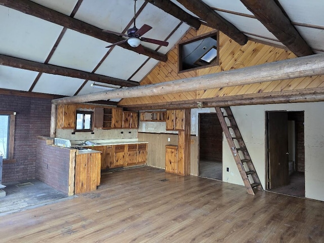 kitchen with brick wall, ceiling fan, beamed ceiling, wood finished floors, and brown cabinetry