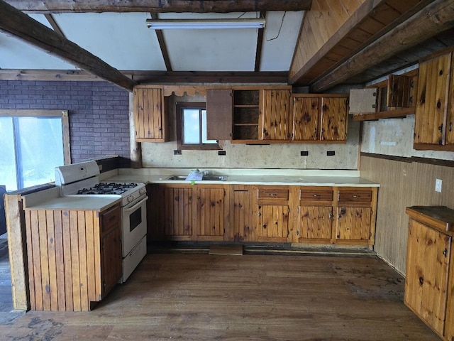 kitchen with dark wood-type flooring, brown cabinets, white gas range oven, and a sink