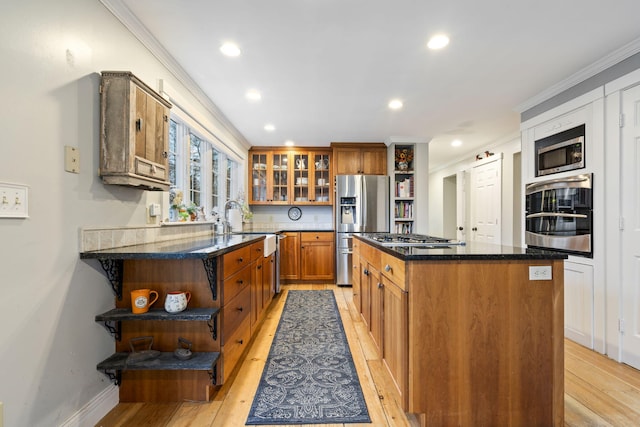 kitchen featuring a center island, light hardwood / wood-style flooring, dark stone counters, ornamental molding, and stainless steel appliances