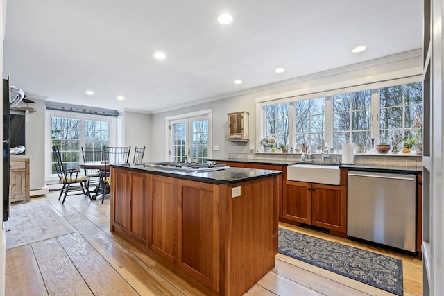 kitchen featuring sink, crown molding, light wood-type flooring, appliances with stainless steel finishes, and a kitchen island