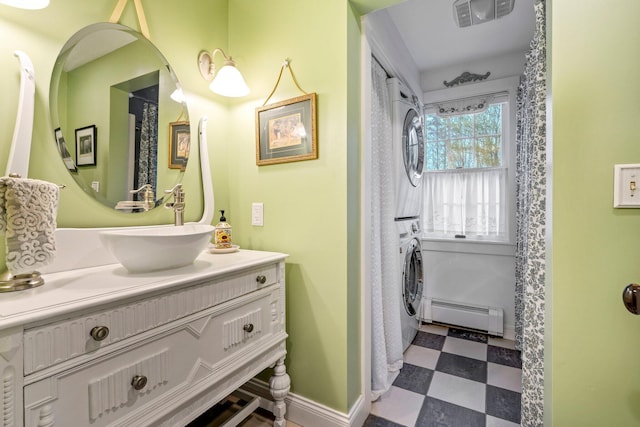 bathroom featuring stacked washer / dryer, vanity, and baseboard heating