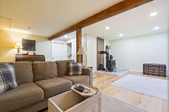 living room with beamed ceiling, hardwood / wood-style flooring, and a wood stove