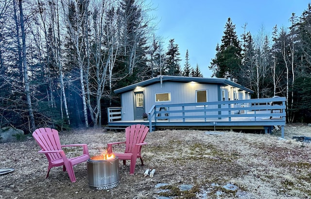 rear view of house with a wooden deck and a fire pit