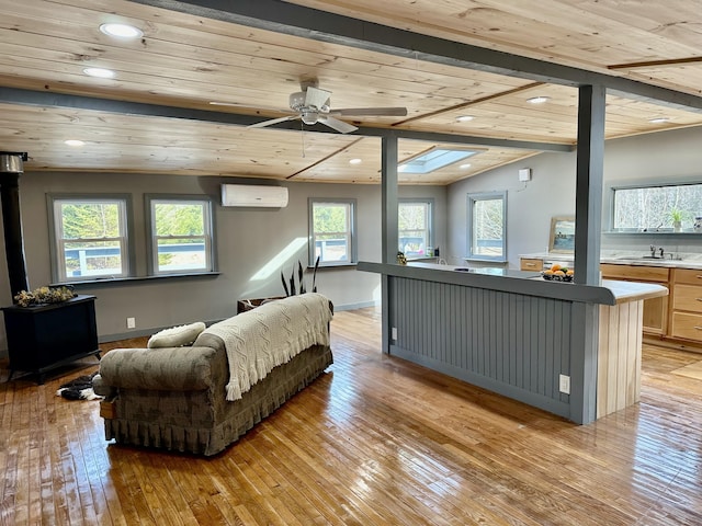 living room featuring sink, wooden ceiling, light wood-type flooring, a wall unit AC, and vaulted ceiling with skylight