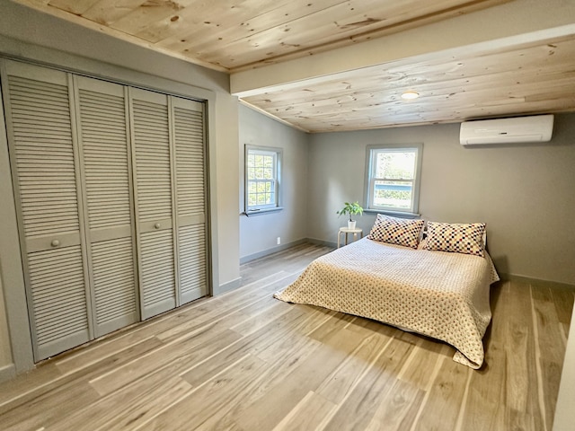 bedroom with multiple windows, a wall mounted AC, and light hardwood / wood-style flooring