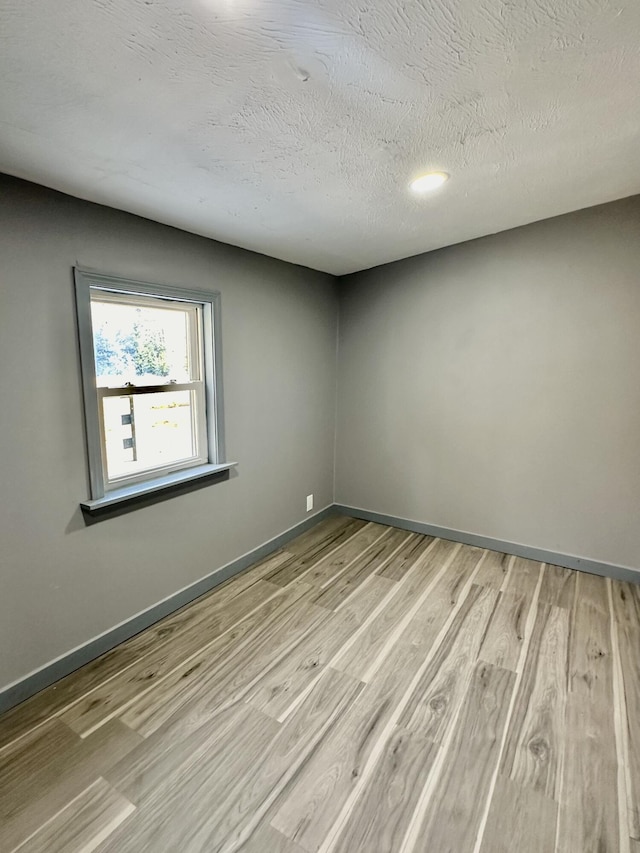 empty room with light hardwood / wood-style flooring and a textured ceiling