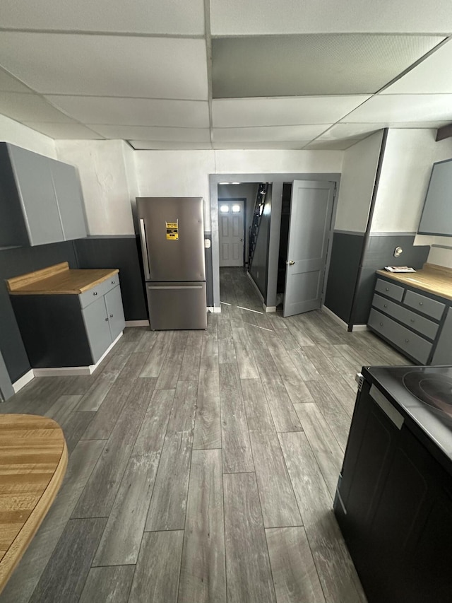 kitchen with freestanding refrigerator, wood tiled floor, light countertops, gray cabinetry, and a paneled ceiling