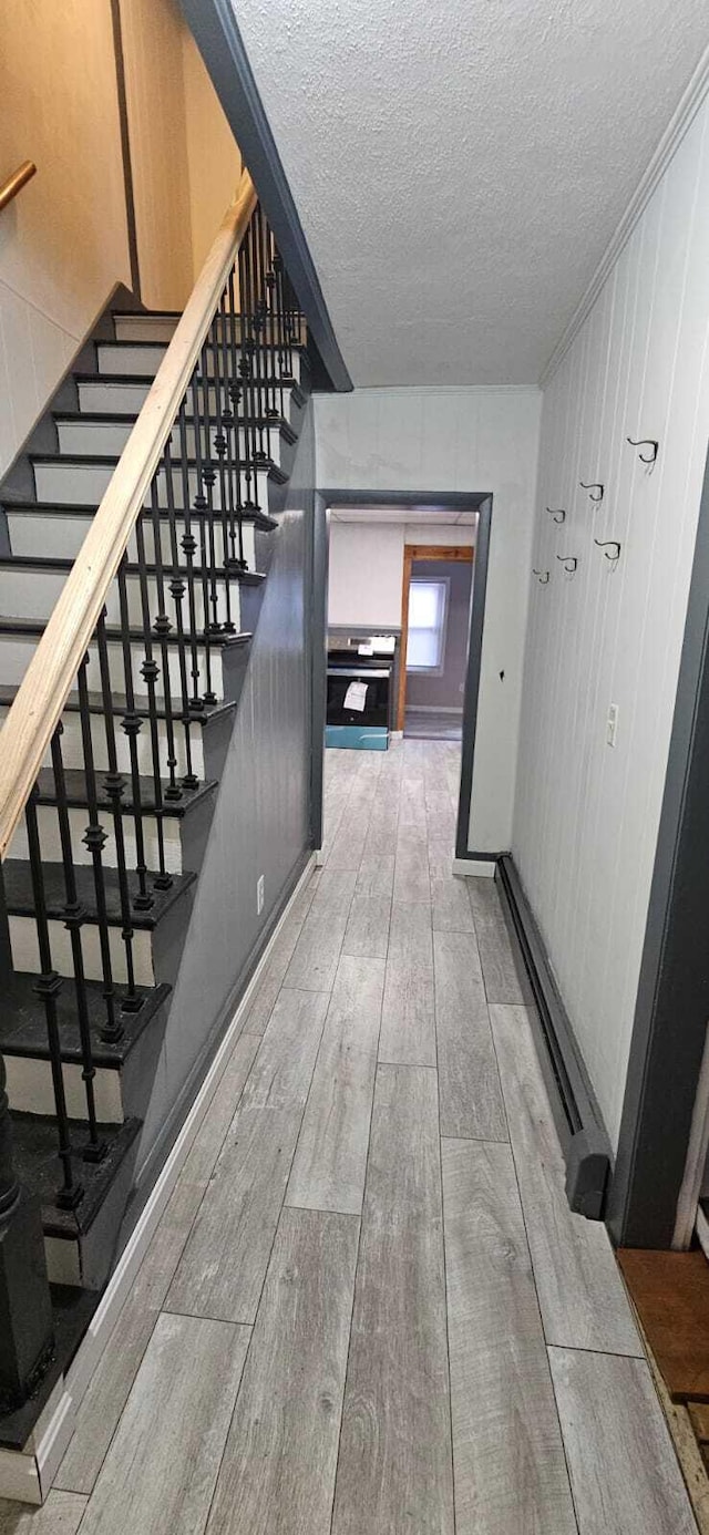 hallway featuring a textured ceiling, stairway, and wood finished floors