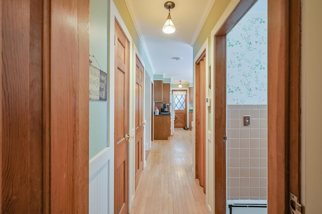 hallway featuring ornamental molding, tile walls, and light hardwood / wood-style flooring