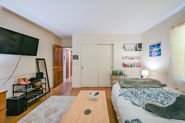 bedroom featuring crown molding, light hardwood / wood-style flooring, and a closet