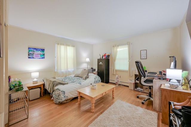 bedroom with light wood-type flooring and a baseboard heating unit