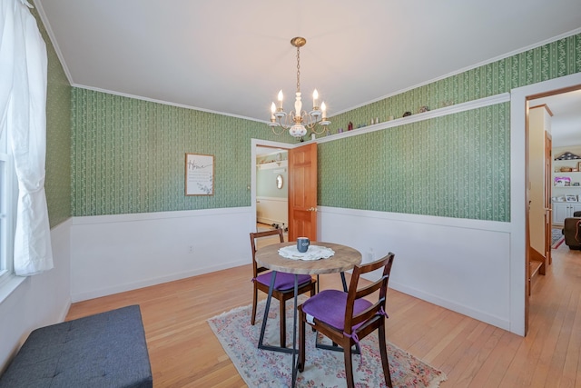 dining space with crown molding, an inviting chandelier, and hardwood / wood-style flooring