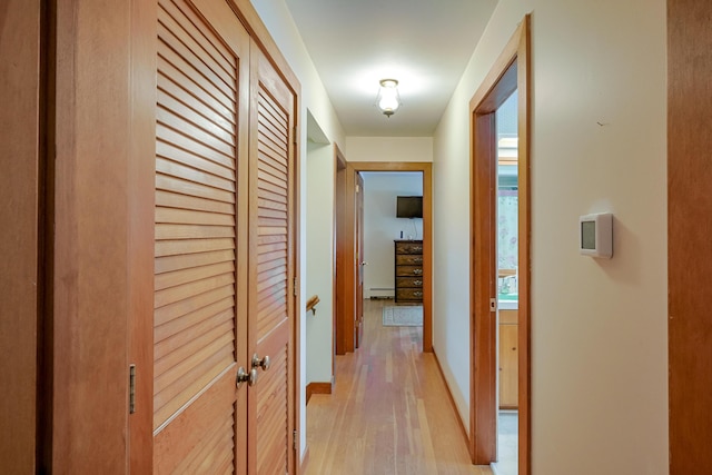 corridor with a baseboard heating unit and light hardwood / wood-style flooring