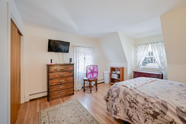 bedroom featuring lofted ceiling, a baseboard radiator, a closet, and light wood-type flooring