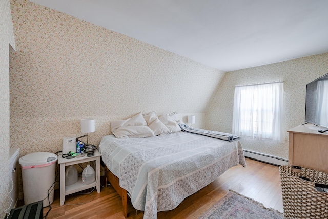 bedroom featuring a baseboard heating unit and wood-type flooring