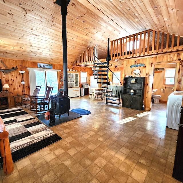 bedroom with wood ceiling, high vaulted ceiling, a wood stove, wooden walls, and washer / clothes dryer