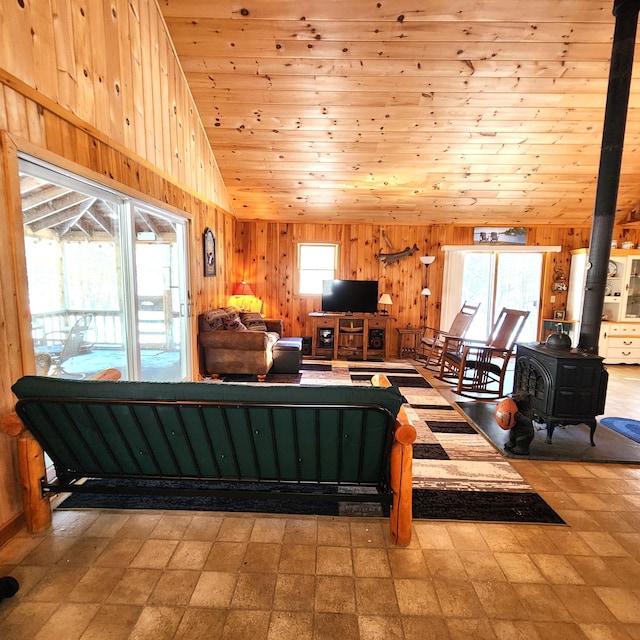 living room with wood ceiling, wood walls, vaulted ceiling, and a wood stove