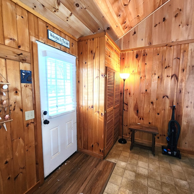 doorway to outside featuring vaulted ceiling, wooden ceiling, and wood walls