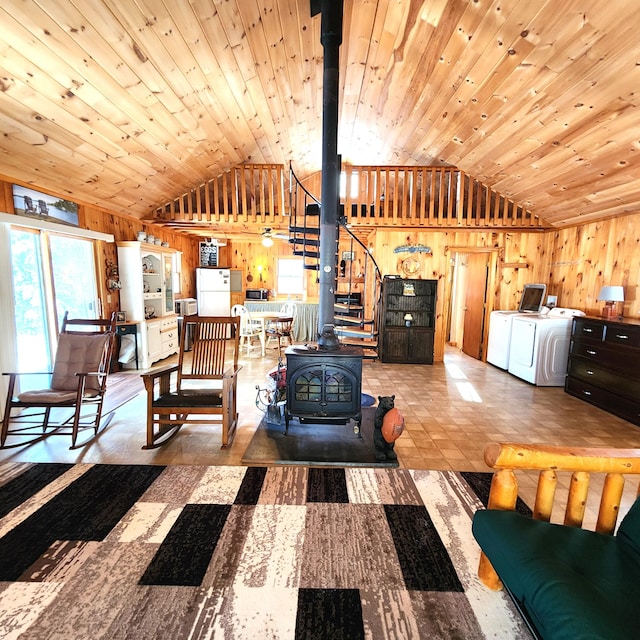 living room featuring wooden walls, washing machine and dryer, wooden ceiling, and a wood stove