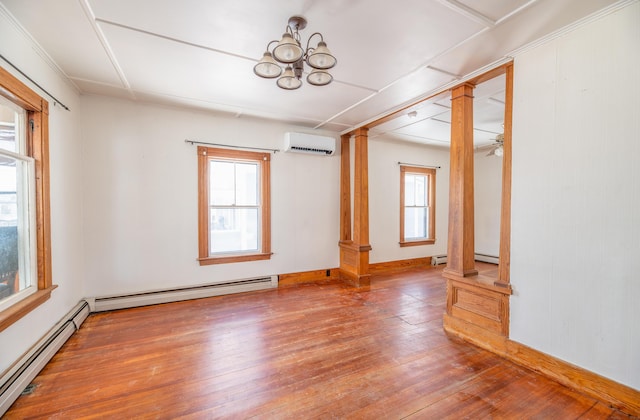 unfurnished room featuring decorative columns, a wall unit AC, and a baseboard heating unit