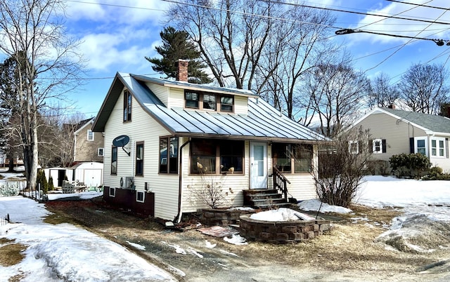 view of front of property featuring entry steps, a chimney, metal roof, a standing seam roof, and an outdoor structure