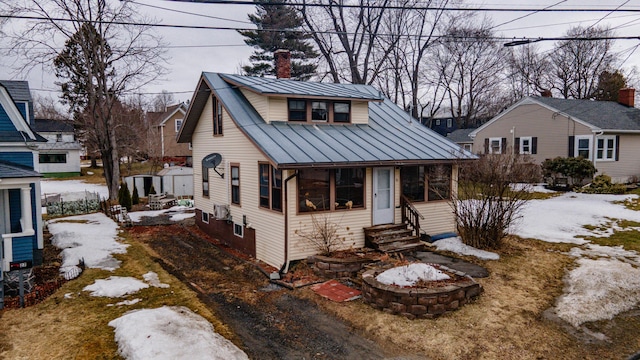 bungalow-style home with a standing seam roof, a chimney, entry steps, and metal roof