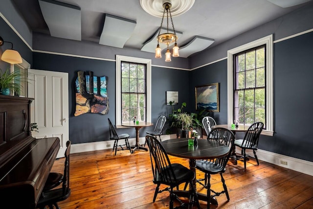 dining space with a wealth of natural light, hardwood / wood-style floors, and a chandelier