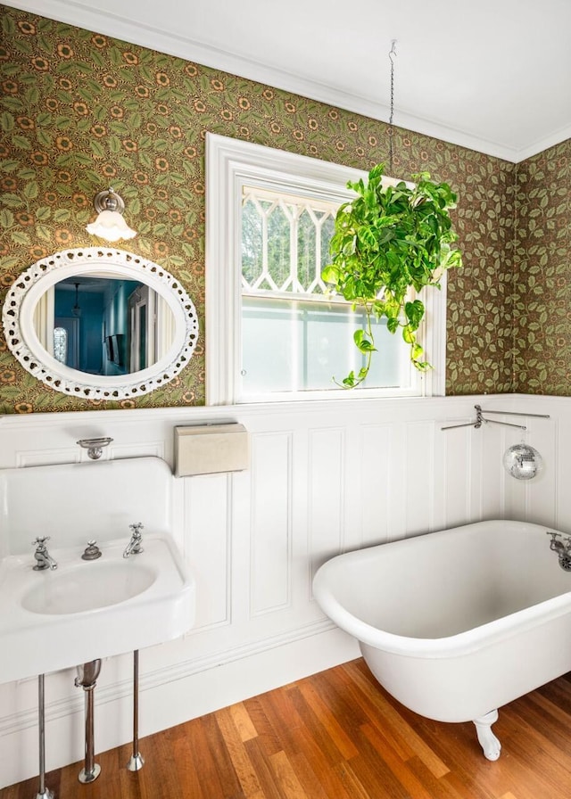 bathroom featuring hardwood / wood-style flooring, ornamental molding, and a tub