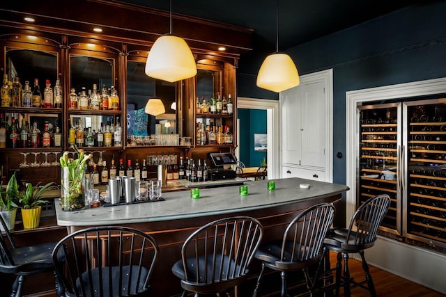 bar featuring light stone counters and hanging light fixtures