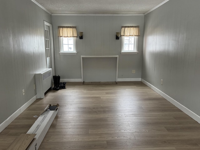 spare room with ornamental molding, radiator, and wood-type flooring