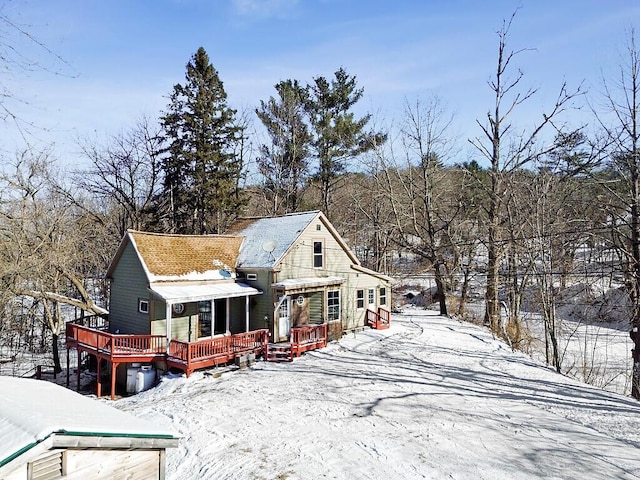 snow covered rear of property with a wooden deck