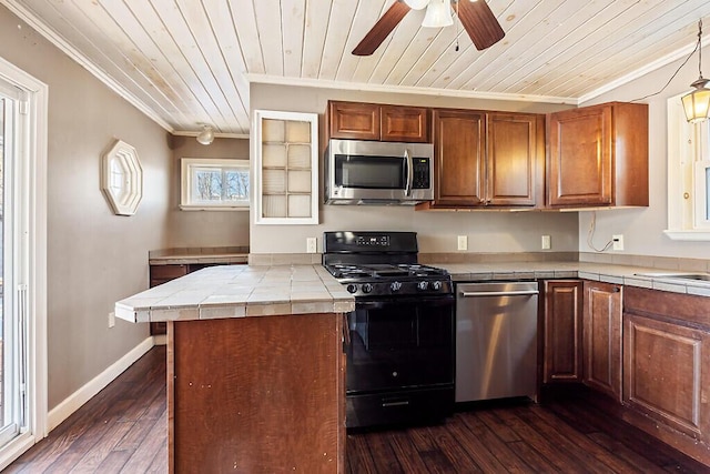 kitchen featuring dark wood-type flooring, ornamental molding, tile counters, kitchen peninsula, and stainless steel appliances