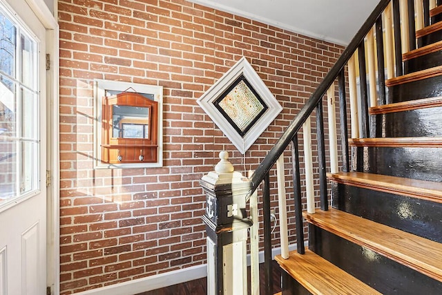 stairway with brick wall and hardwood / wood-style floors