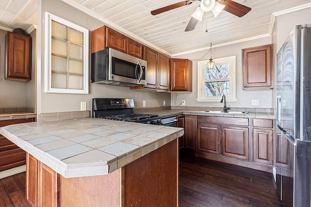 kitchen featuring sink, appliances with stainless steel finishes, decorative light fixtures, tile countertops, and kitchen peninsula