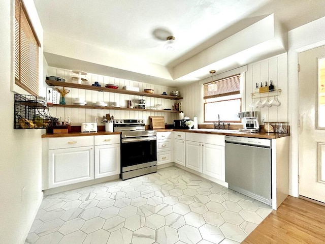 kitchen with white cabinetry, sink, a tray ceiling, and appliances with stainless steel finishes