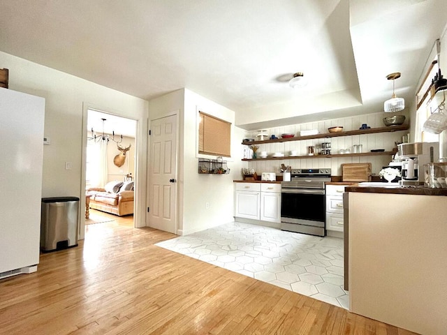 kitchen featuring stainless steel electric stove, pendant lighting, white cabinets, white fridge, and light hardwood / wood-style floors