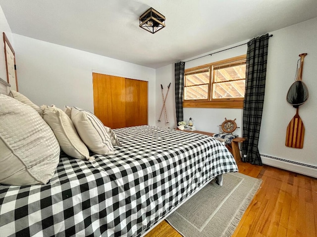 bedroom with a baseboard radiator, a closet, and light hardwood / wood-style flooring