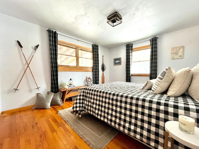 bedroom with multiple windows, wood-type flooring, and a textured ceiling