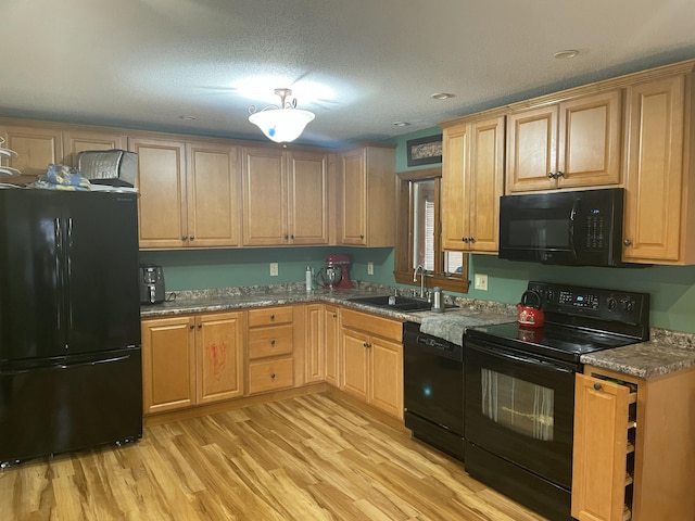 11 Partridge Dr, Gardiner, ME 04345 - kitchen with light wood-style flooring, light stone countertops, a textured ceiling, black appliances, and a sink