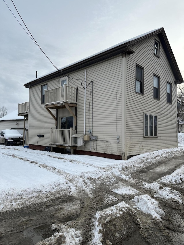 snow covered rear of property with a balcony