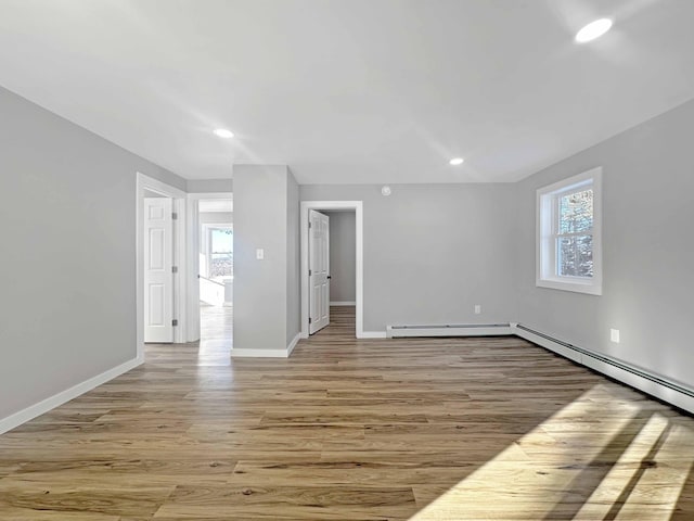 spare room with a baseboard heating unit, plenty of natural light, and light hardwood / wood-style floors