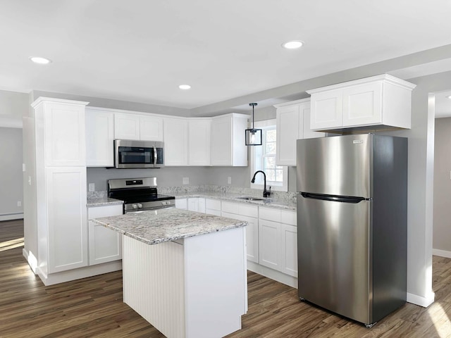 kitchen featuring sink, appliances with stainless steel finishes, white cabinetry, hanging light fixtures, and a kitchen island