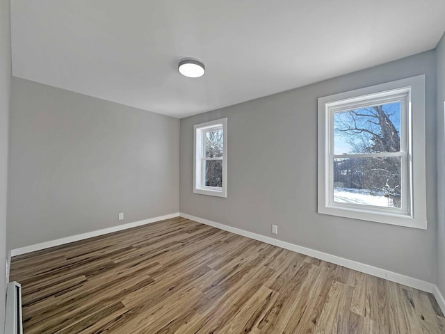 spare room with a baseboard radiator and light wood-type flooring