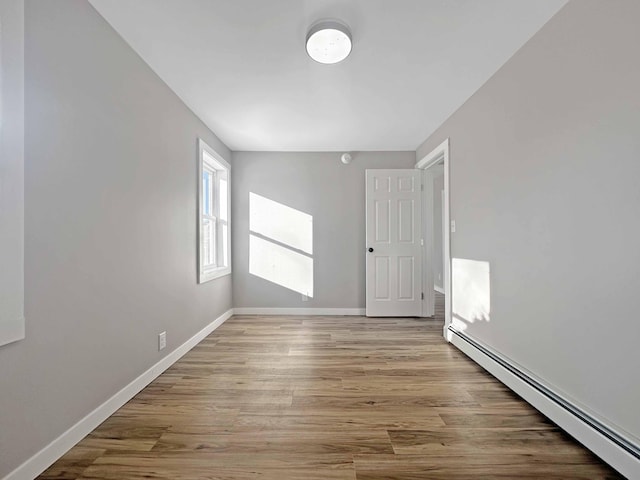 unfurnished room with baseboard heating and light hardwood / wood-style floors