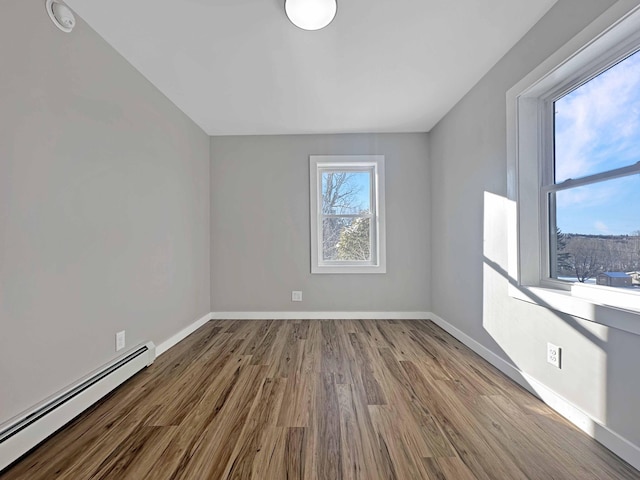 empty room with a baseboard heating unit and light hardwood / wood-style flooring