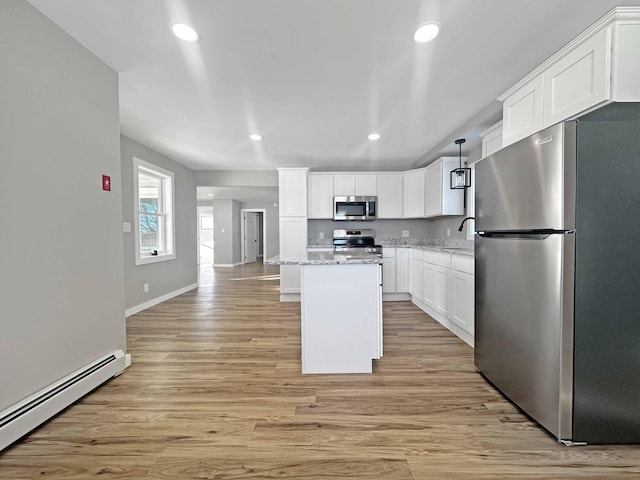 kitchen featuring appliances with stainless steel finishes, white cabinetry, a baseboard heating unit, a center island, and light stone counters